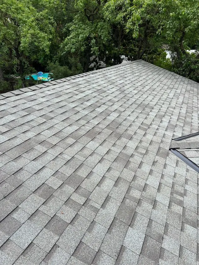 Completed shingle roof surrounded by green trees