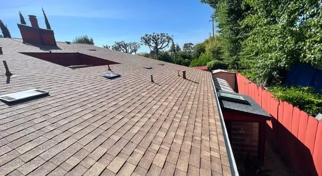 Tan shingle roof replacement with red fence in Fresno